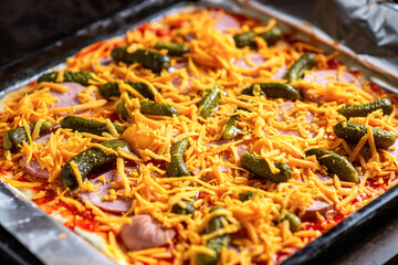 Raw pizza with pickles and cheese. Cooking homemade pizza.