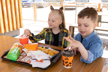 Stavropol, Russia - 27.05.2023 - Children brother and sister eat nuggets and french fries at fast...