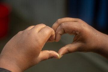 A young man shows his both hand with signs of love and a background blur