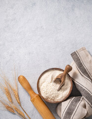 Natural flour in a wooden bowl with a scoop, rolling pin and napkin on a blue background with...