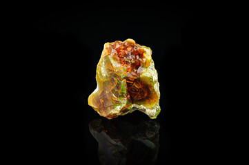 fire opal isolated on black background. macro detail close-up rough raw unpolished semi-precious gemstone.