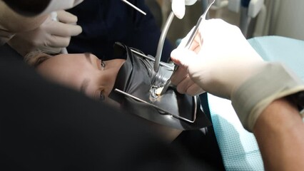 The process of treating the teeth of a young woman using modern technologies and tools. 