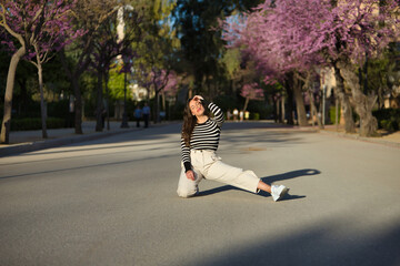 Young and beautiful woman, Hispanic, brown hair, with striped sweater, linen pants, bending down...