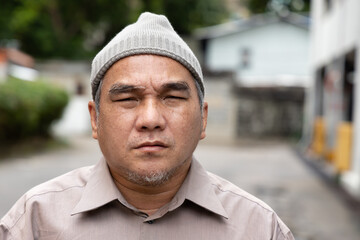 Old man cancer patient wearing grey chemotherapy hat after suffering from hair loss due to...