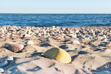 Yellow sand pebble in focus  and the blurred sea in the background