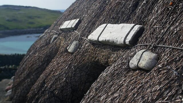 Static shot of a thatched roof on a blackhouse. This was filmed at the Gearrannan Blackhouse Village, a museum and recreation of a historic, Scottish blackhouse township. Filmed on the Outer Hebrides.