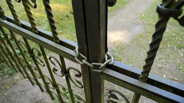 Chain on a metal fence with a garden behind it
