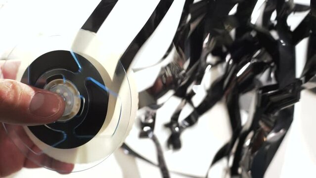 Unspooling the VHS tape from the reel inside the cassette