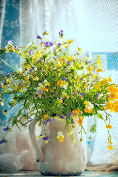 A lovely bouquet of wild flowers in an earthenware jug by the window on the veranda. Vintage village photo.
