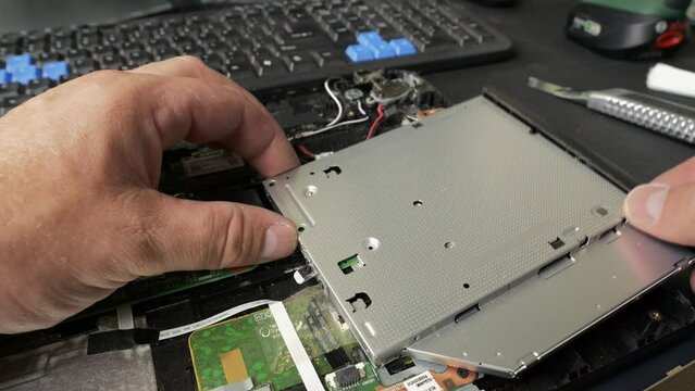 Repair of an old laptop, the technician is removing the CD drive