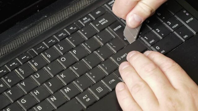 Repair of an old laptop, the technician uses a small knife to remove the CTRL key