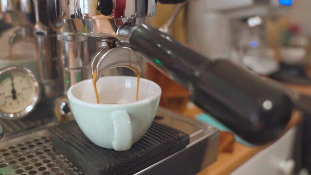 Espresso pouring into white coffee cup. Closeup with professional coffee machine