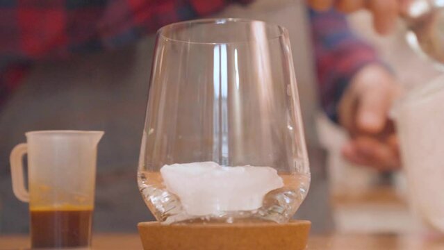 Iced coffee preparation. Putting ice in glass. Closeup, slow motion
