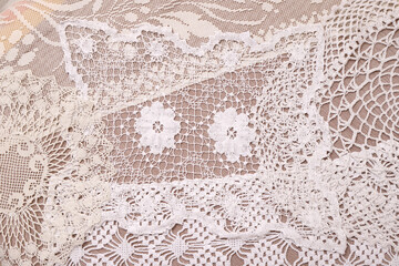 a background or picture on the wall consisting of a large number of crocheted things; Beautiful delicate vintage lace background of crochet doily on the table 