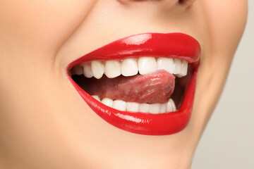 Woman showing her tongue on light background, closeup