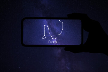 Woman using stargazing app on her phone at night, closeup. Identified stick figure pattern of...