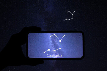 Man using stargazing app on his phone at night, closeup. Identified stick figure pattern of Sagittarius (Archer) constellation on device screen