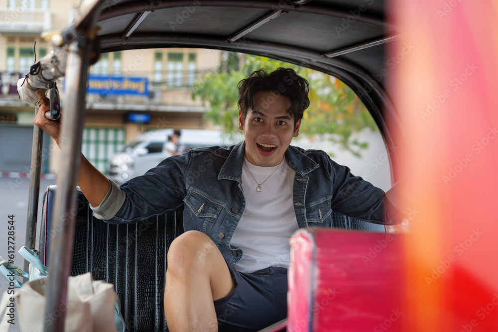 Wall mural Happy and joyful Young Asian male traveler tourists riding a tuk tuk tour, rickshaw style transportation on the street in Bangkok, Thailand - people traveling enjoying local culture concept