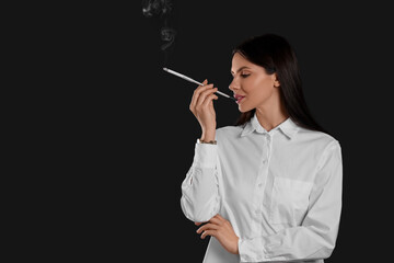 Obraz premium Woman using long cigarette holder for smoking on black background, space for text
