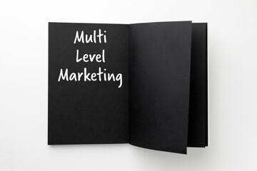 Multi Level Marketing written in notebook with black pages on white background, top view