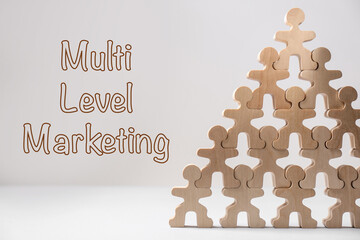 Multi-level marketing. Pyramid of wooden human figures on white table