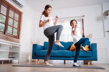 Obraz premium Mother and daughter exercising together happily at home. for flexibility build muscle strength, Sport workout training family together concept.