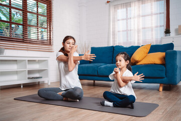 Obraz premium Mother and daughter exercising together happily at home. for flexibility build muscle strength, Sport workout training family together concept.