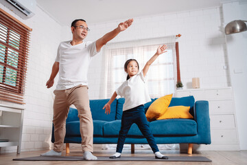 Obraz premium Father and daughter exercising together happily at home. for flexibility build muscle strength, Sport workout training family together concept.