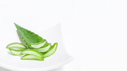 Fototapeta premium Fresh aloe leaf and sliced aloe slices on a white plate. On a white background
