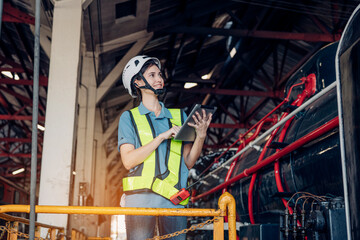 Portrait of professional woman engineer in white hardhat standing and holding tablet working in train factory.	