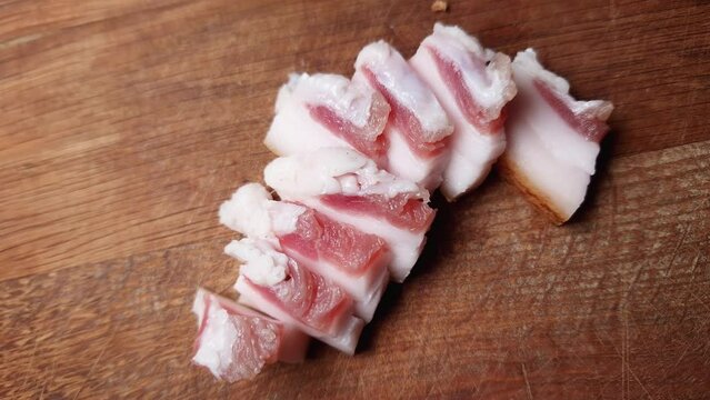 Slices of salted pork fatback on cutting board, close-up