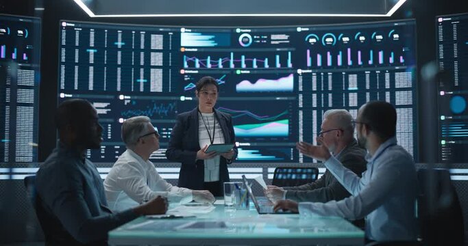 Management Meeting in a Big Data Monitoring Company. Diverse Team of Data Scientists Discussing Graphs and Reports on a Big Digital Screen in the Office. Female Team Leader is Making a Presentation