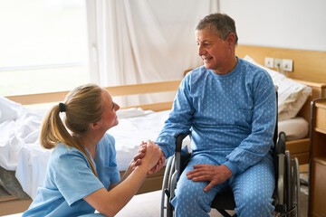Obraz premium Nurse holding hand of senior man at rehab center