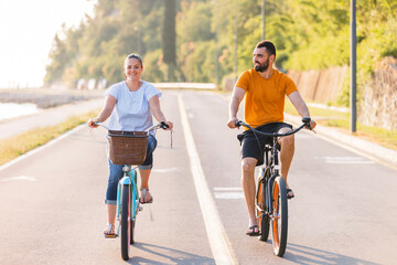 Couple taking pleasure in the ride on beach cruiser bikes, pedaling on a wonderful route near the...