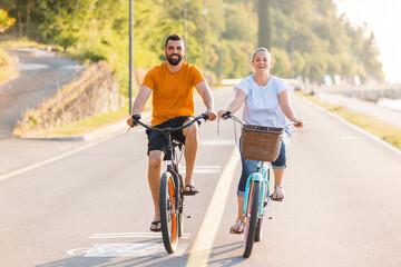 Fototapeta na wymiar Couple taking pleasure in the ride on beach cruiser bikes, pedaling on a wonderful route near the sea