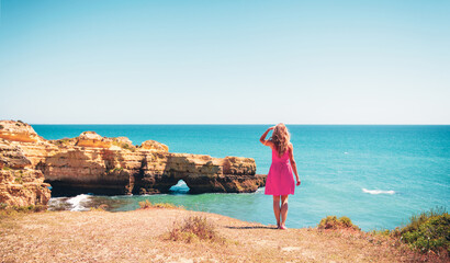 Woman with red dress looking at beautiful sea- Portugal,  Algarve