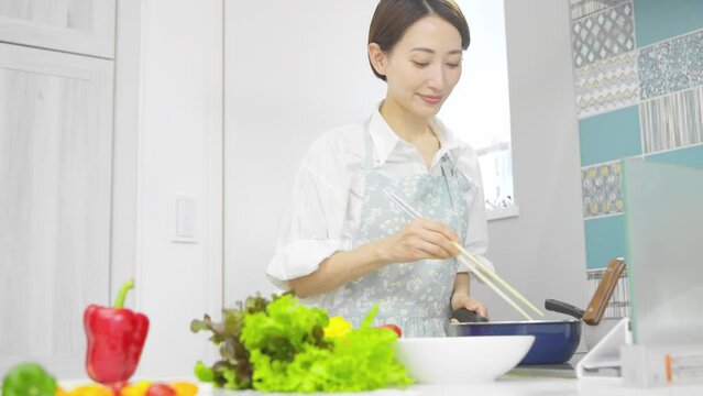 野菜炒めを作る若い女性　料理イメージ	
