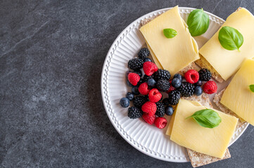 Healthy breakfast with low carb crispbread, old gouda cheese and fresh berries isolated on dark background. Top view