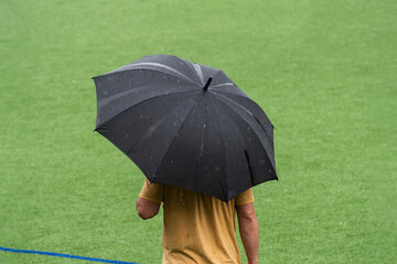 coach with umbrella on the soccer field