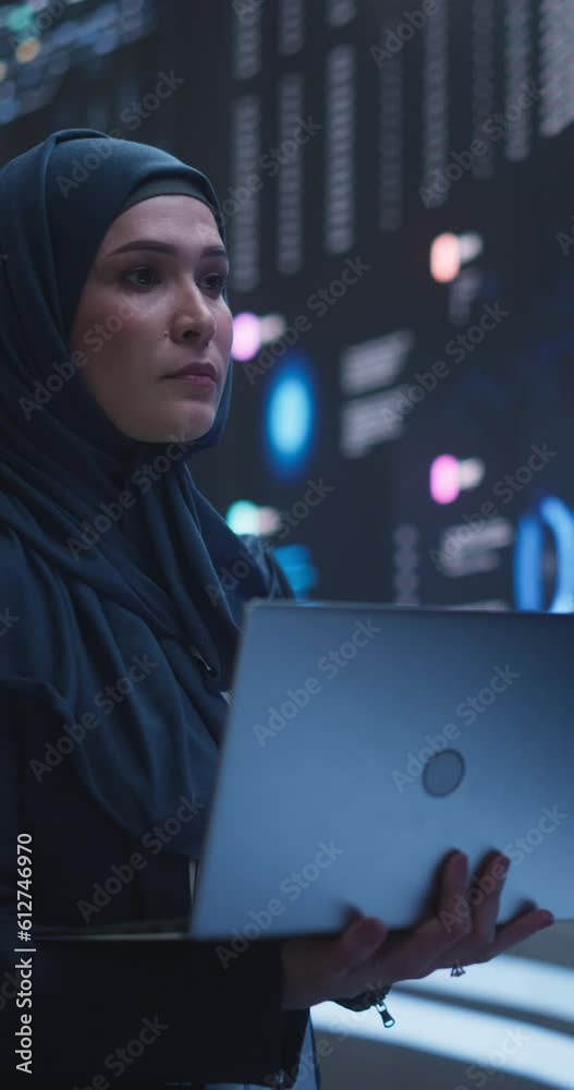 Poster vertical screen: arab female working in an advanced technology company. woman wearing a hijab, using
