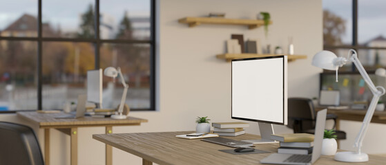 A computer mockup with office supplies on a table in a modern minimal co-working office.