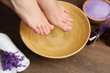 Obraz na płótnie Canvas Woman soaking her feet in bowl with water, closeup. Pedicure procedure