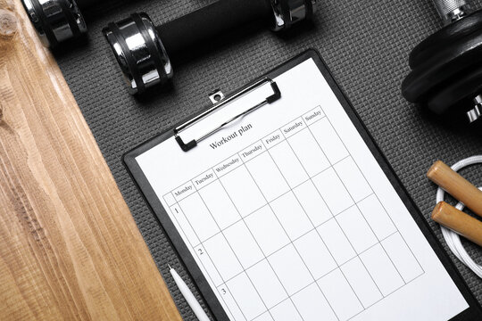 Clipboard with workout plan and sports equipment on wooden table, flat lay. Personal training