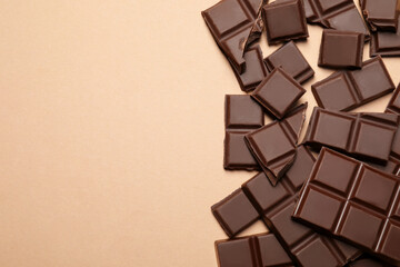 Pieces of delicious chocolate bars on beige background, flat lay. Space for text