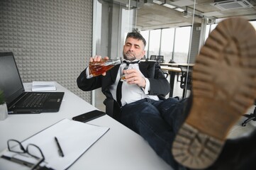 Alcoholism at work. Tired employee drinking alcohol at workplace, can not handle stress