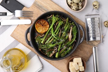 Tasty cooked broccolini, mushrooms and lemon on white marble table, flat lay