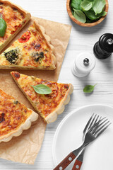 Delicious homemade vegetable quiche, spices and forks on white wooden table, flat lay