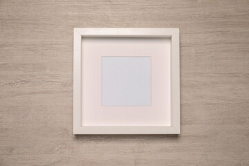 Empty photo frame on wooden background, top view. Mockup for design
