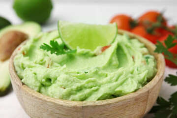 Bowl of delicious guacamole with lime, closeup