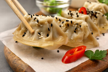 Taking delicious gyoza (asian dumpling) from board at table, closeup